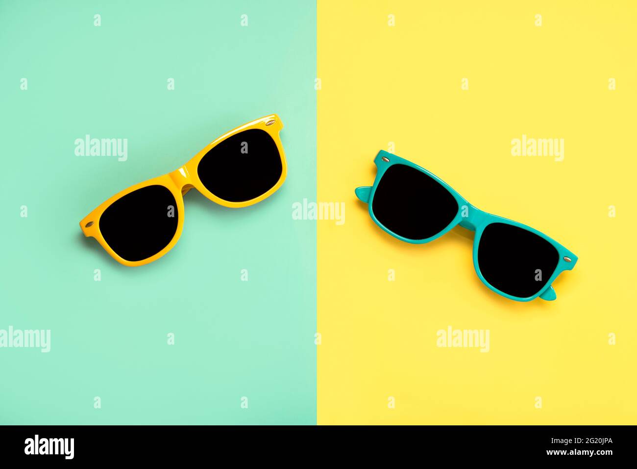 Draufsicht auf grüne und gelbe Sonnenbrille auf grünem und gelbem Hintergrund Stockfoto