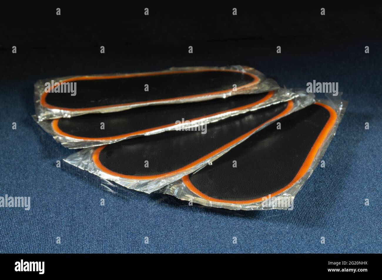 Gummiaufnäher für die Kamera auf dem Tisch mit Reflektion.Radreparaturteile auf schwarzem Hintergrund Stockfoto