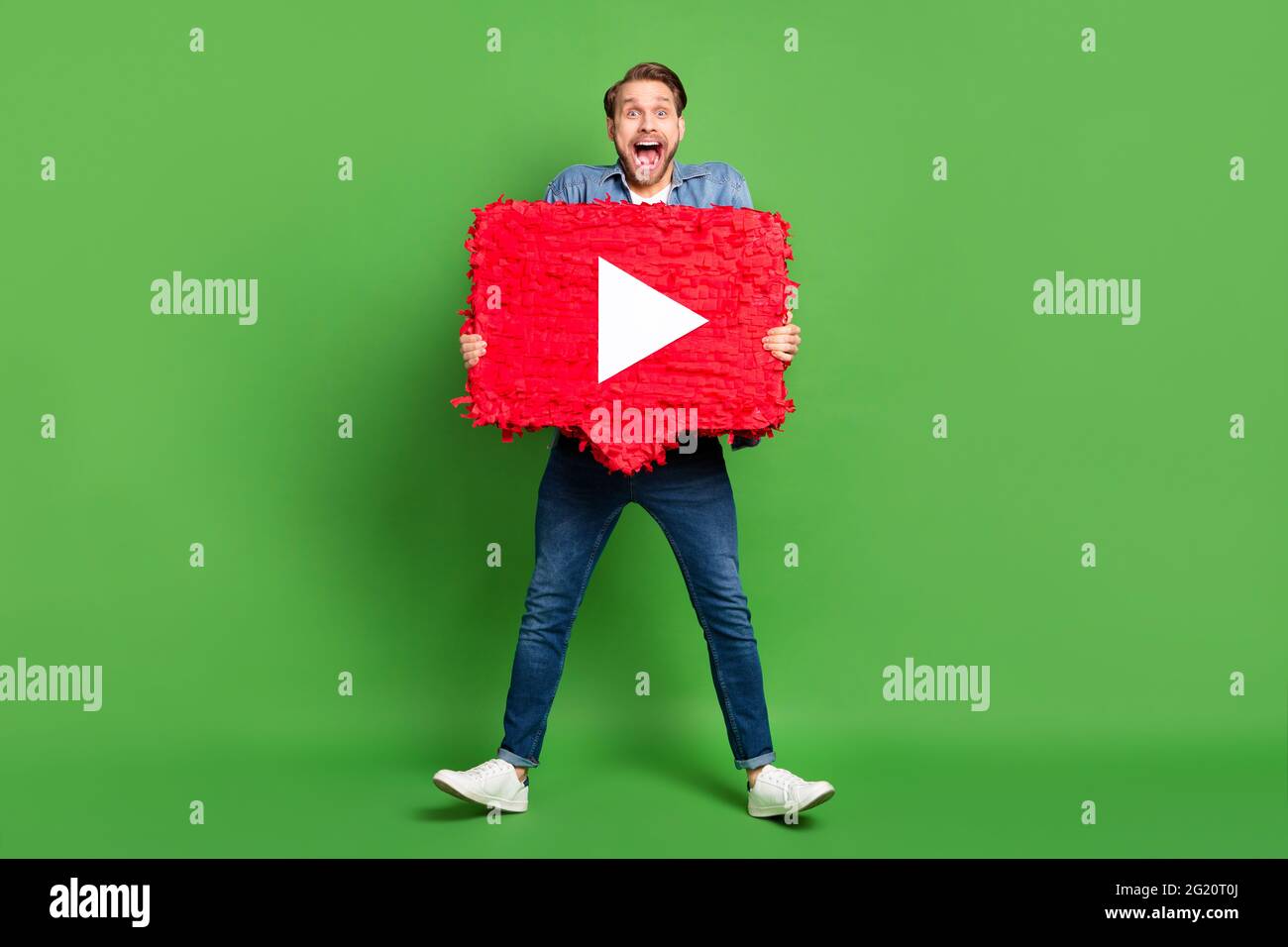 In voller Länge Körpergröße Foto von glücklichen Kerl hält beliebte Stream-Medien-Symbol isoliert lebendige grüne Farbe Hintergrund Stockfoto