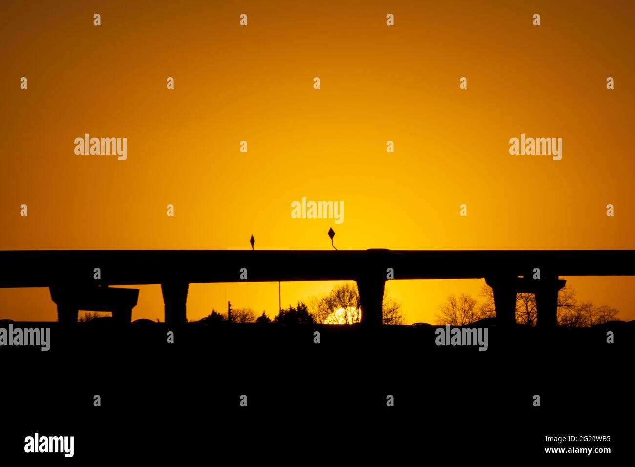 Golden Hour Sonnenuntergang mit einer Brücke Silhouette keine Autos auf der Oberseite. Die Sonne verdunkelt sich am späten Winternachmittag, während sie untergeht. Golden ruhige und ruhige Pendelanfahrtsweg Stockfoto