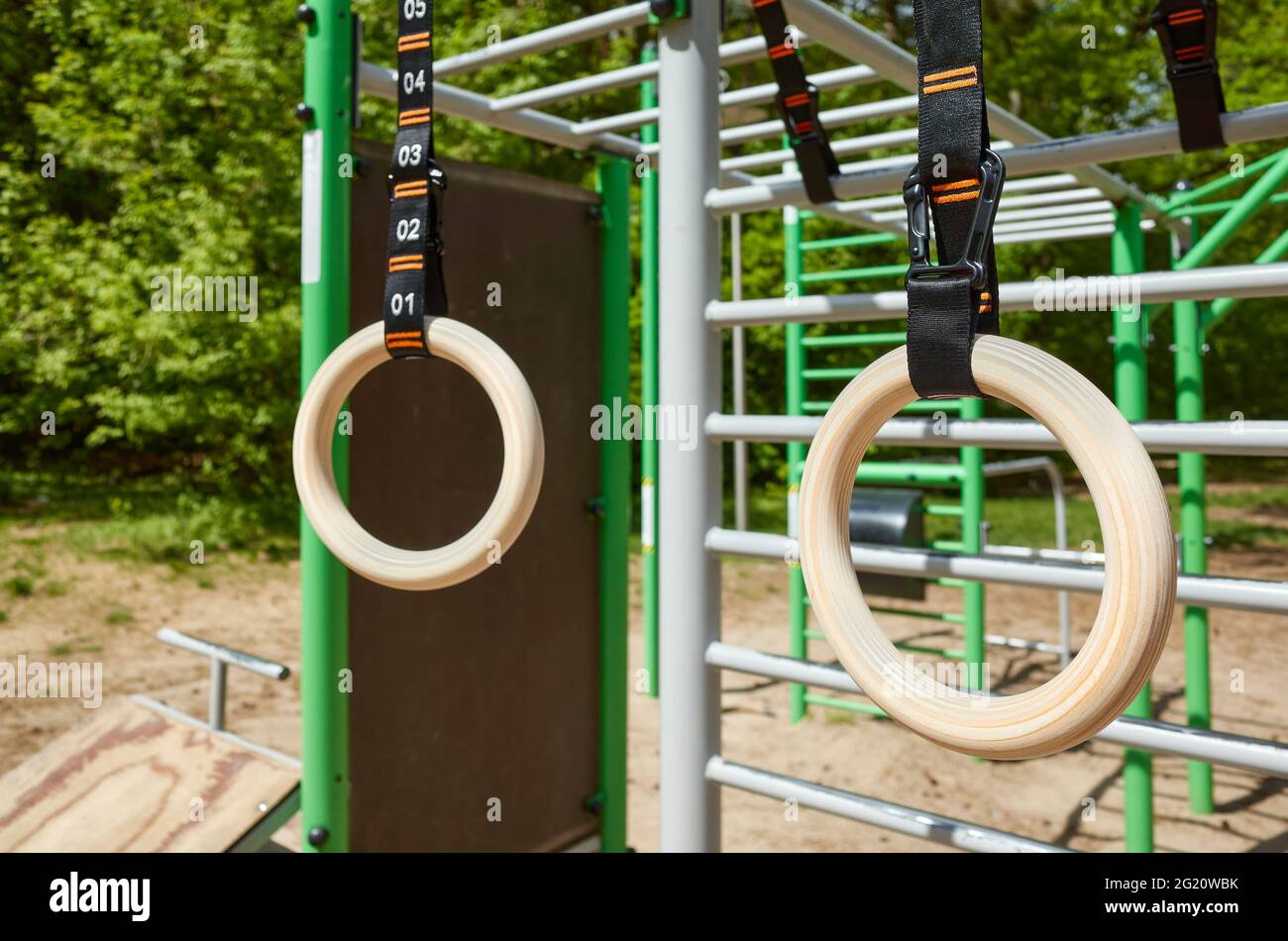Hölzerne Gymnastikringe, die in einer Freilufthalle in einem Park hängen, selektiver Fokus. Stockfoto