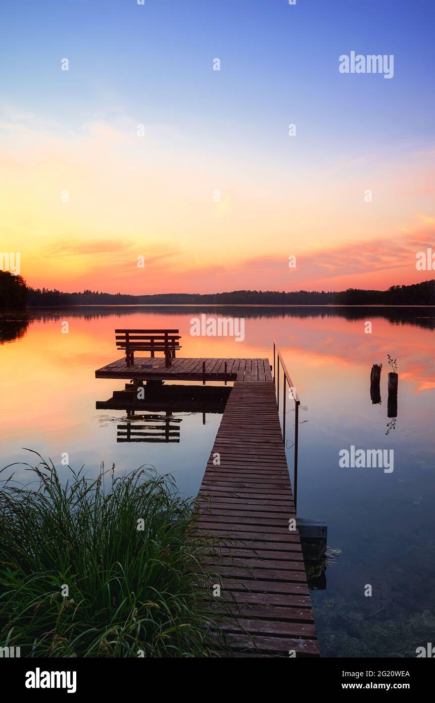 Bank auf einem hölzernen Pier bei Sonnenuntergang, Lipie Lake in Dlugie Village, Polen Stockfoto