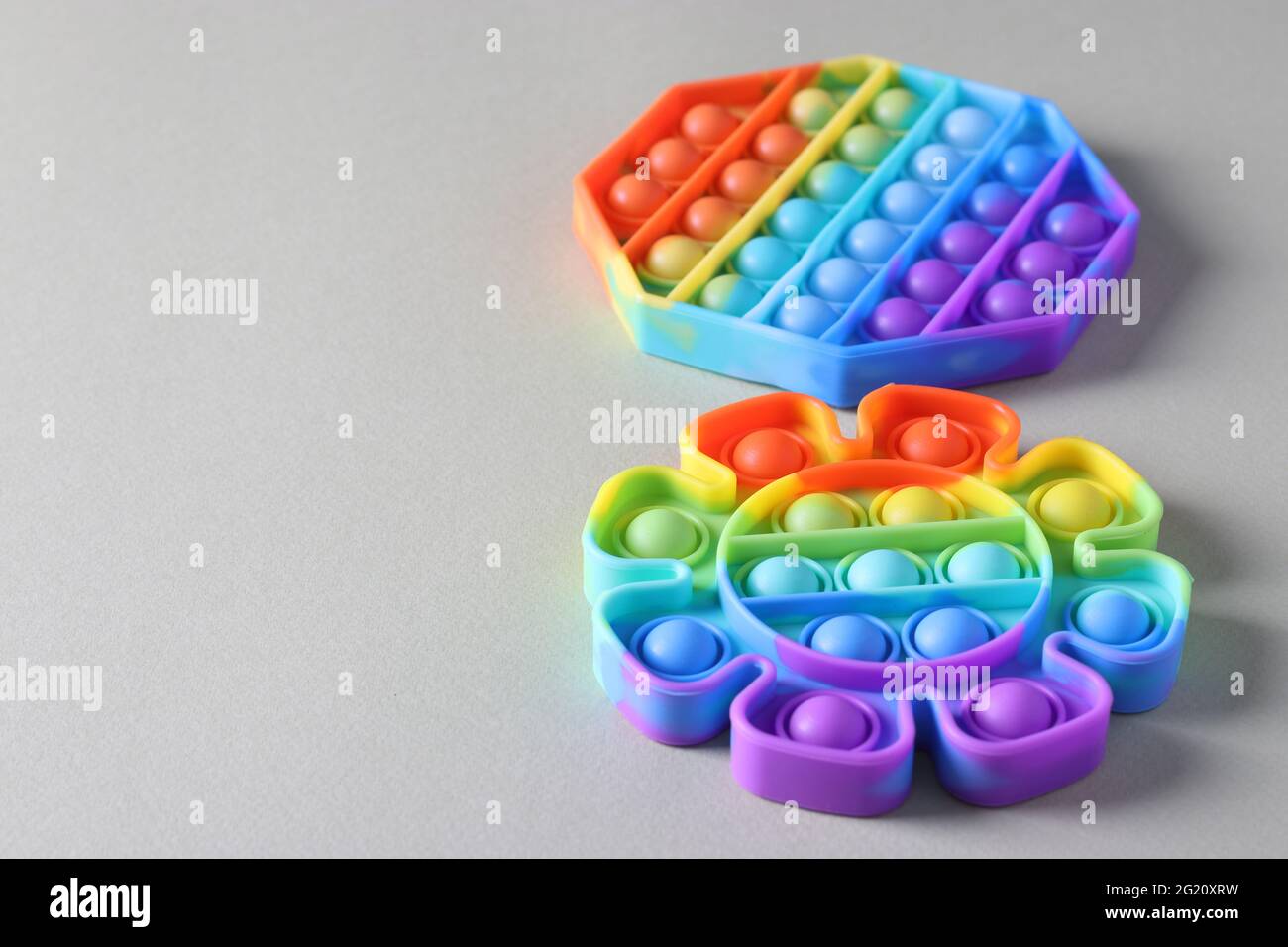 Neue beliebte Silikon bunte Antistress Pop it Spielzeug für Kind auf hellem Hintergrund. Einfache Grübchen. Speicherplatz kopieren Stockfoto