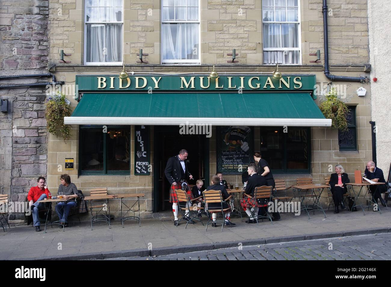 Männliche Mitglieder der schottischen Familie machen vor der Hochzeitszeremonie, die sie in ihrer traditionellen Kleidung tragen, eine Pause im Pub. Stockfoto