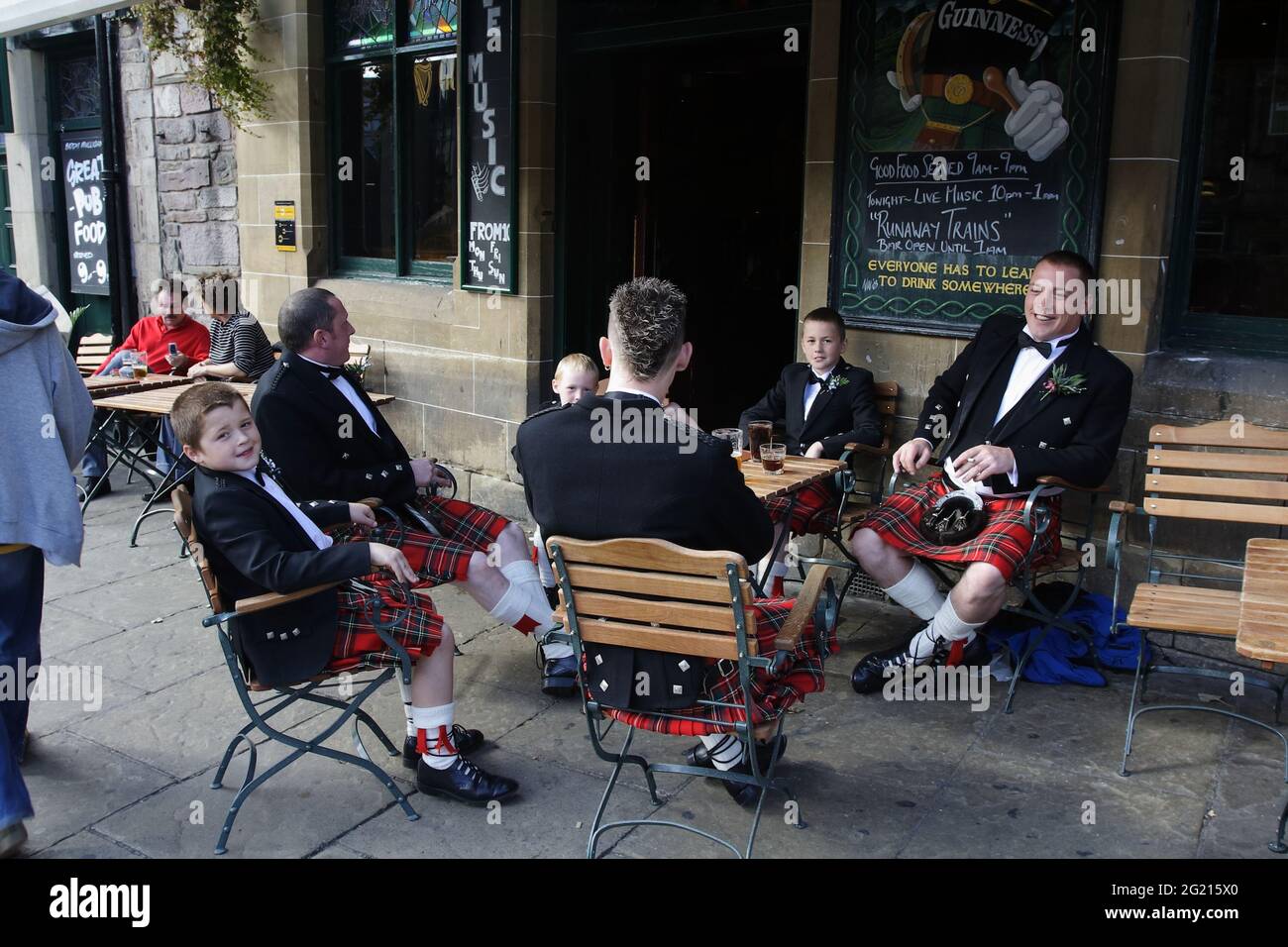 Männliche Mitglieder der schottischen Familie machen vor der Hochzeitszeremonie, die sie in ihrer traditionellen Kleidung tragen, eine Pause im Pub. Stockfoto