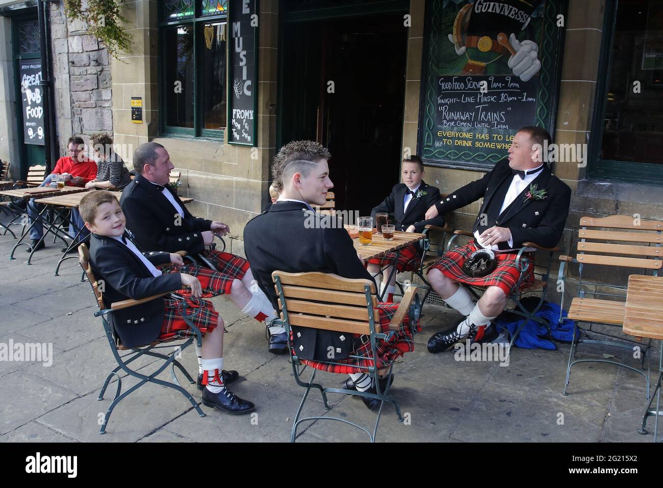Männliche Mitglieder der schottischen Familie machen vor der Hochzeitszeremonie, die sie in ihrer traditionellen Kleidung tragen, eine Pause im Pub. Stockfoto