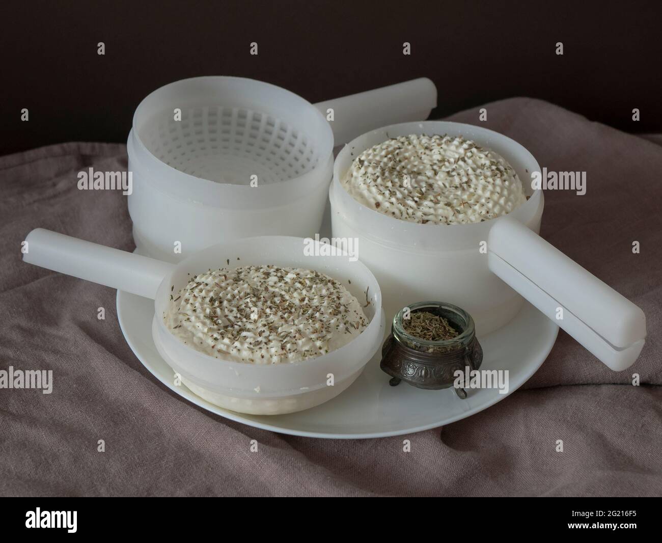 Hausgemachter Rundkäse in einer Käseform mit Herbes Stockfoto