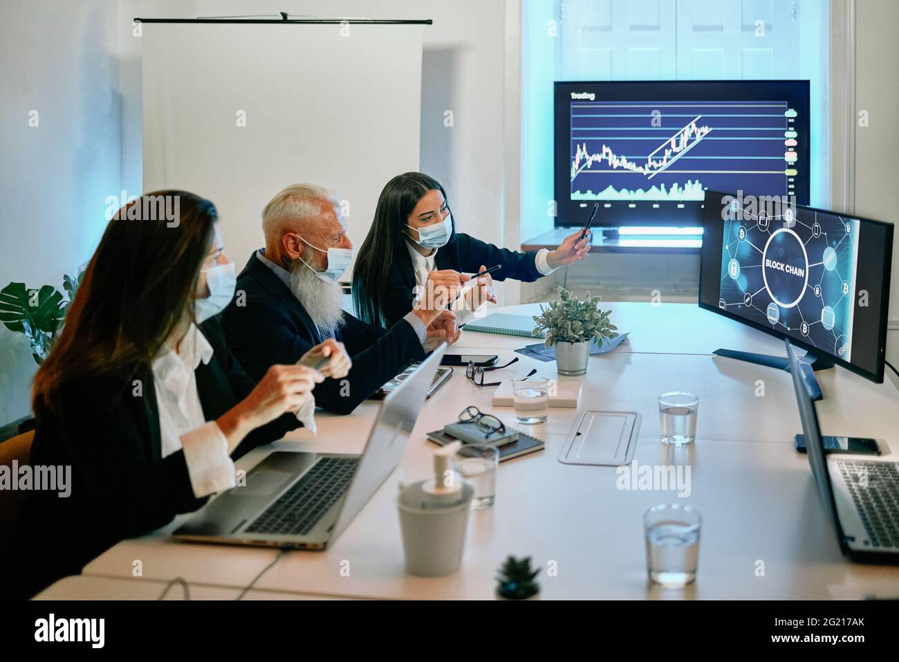 Eine Gruppe von Leuten, die mit einem Laptop an einem Schreibtisch sitzen Stockfoto