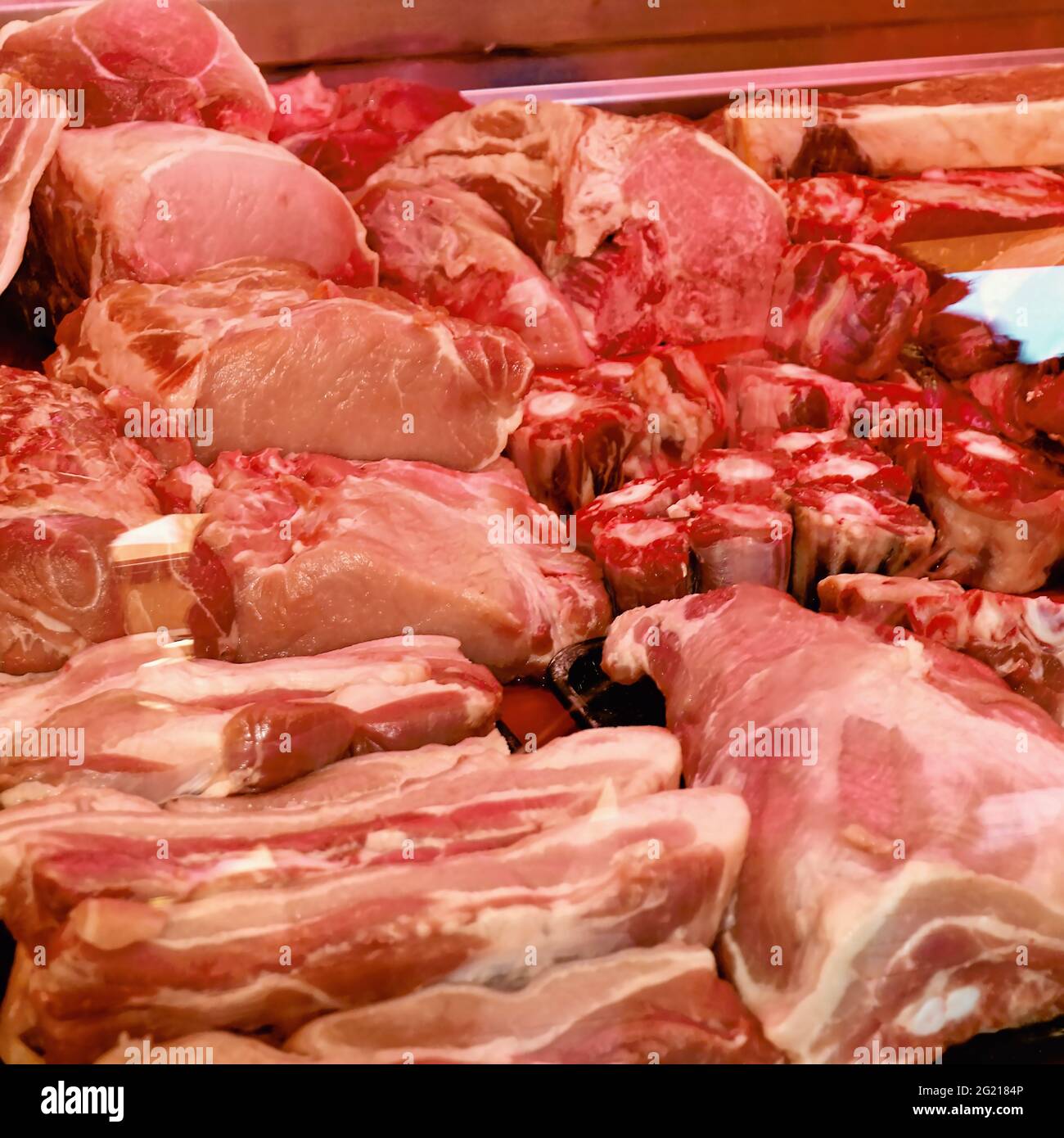 Rohe Schweinefleisch- und Rindfleischstücke aufgereiht und zum Verkauf bereit. Unter anderem Pancetta, Knochenmark, Schnitzel, Sattelrückenfilet, Usw. Stockfoto