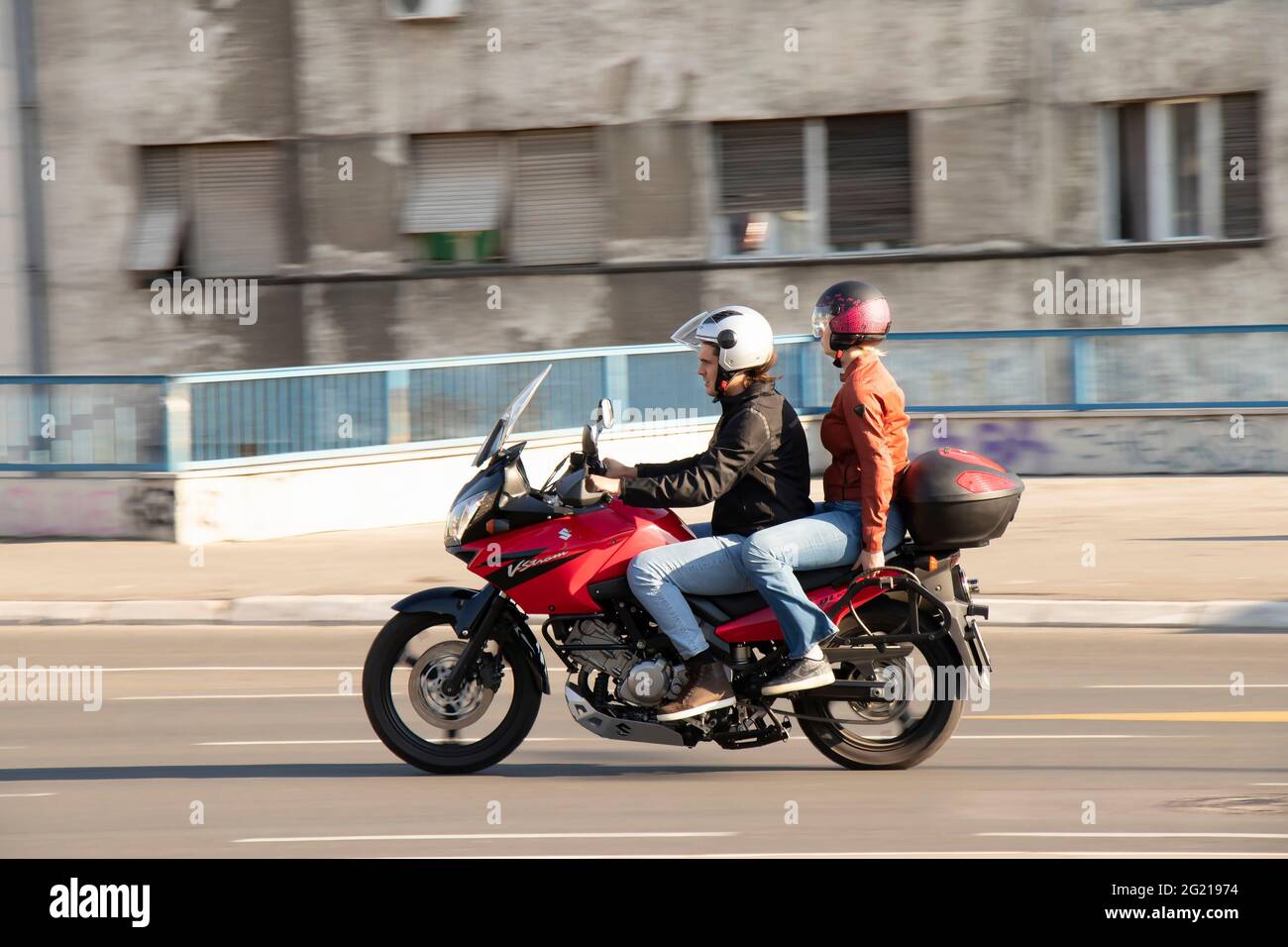 Belgrad, Serbien - 5. Juni 2021: Ehepaar auf einem roten Motorrad, an einem sonnigen Tag auf der Straße der Stadt Stockfoto
