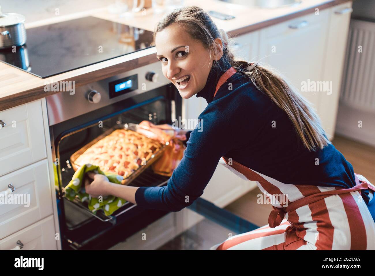 Glückliche Frau, die Kuchen aus dem Ofen entfernt hat Stockfoto