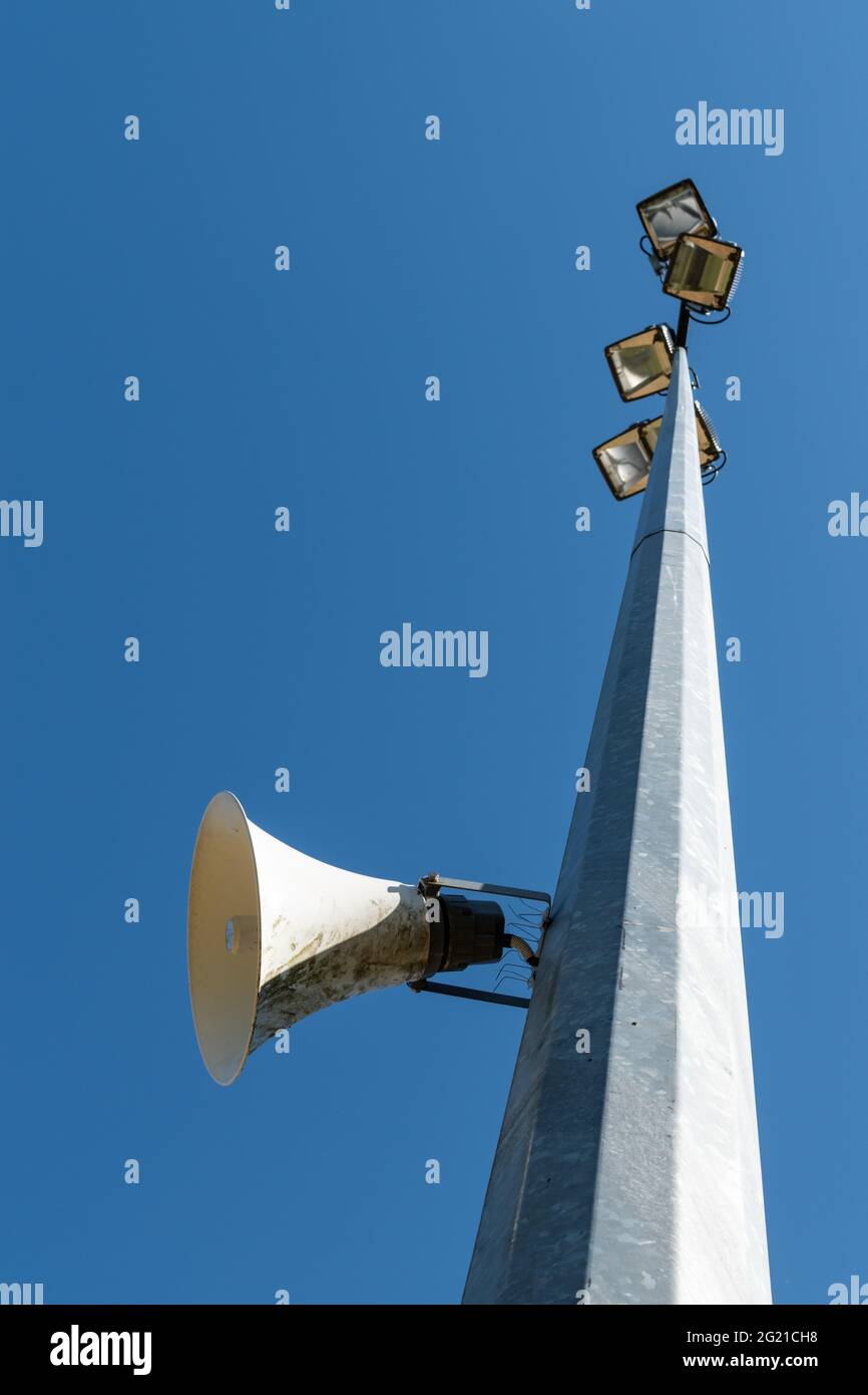 Blick auf einen Turm auf einem Sportplatz mit Lautsprecheranlage und Flutlicht vor dem klaren, blauen Himmel Stockfoto