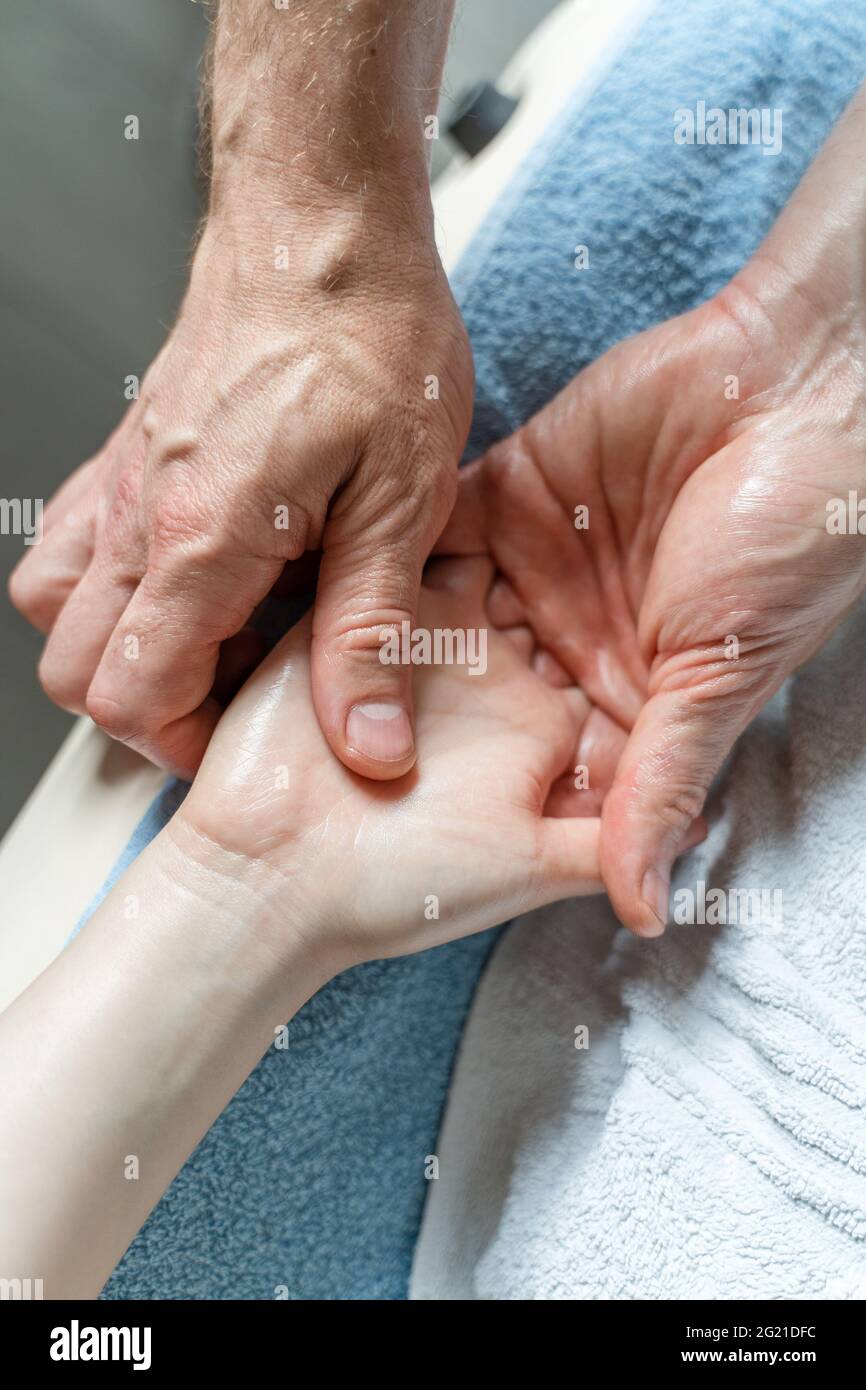 Nahaufnahme der Hände eines unbekannten kaukasischen Therapeuten, der die Hände einer unbekannten Kundin massiert und dehnt Stockfoto