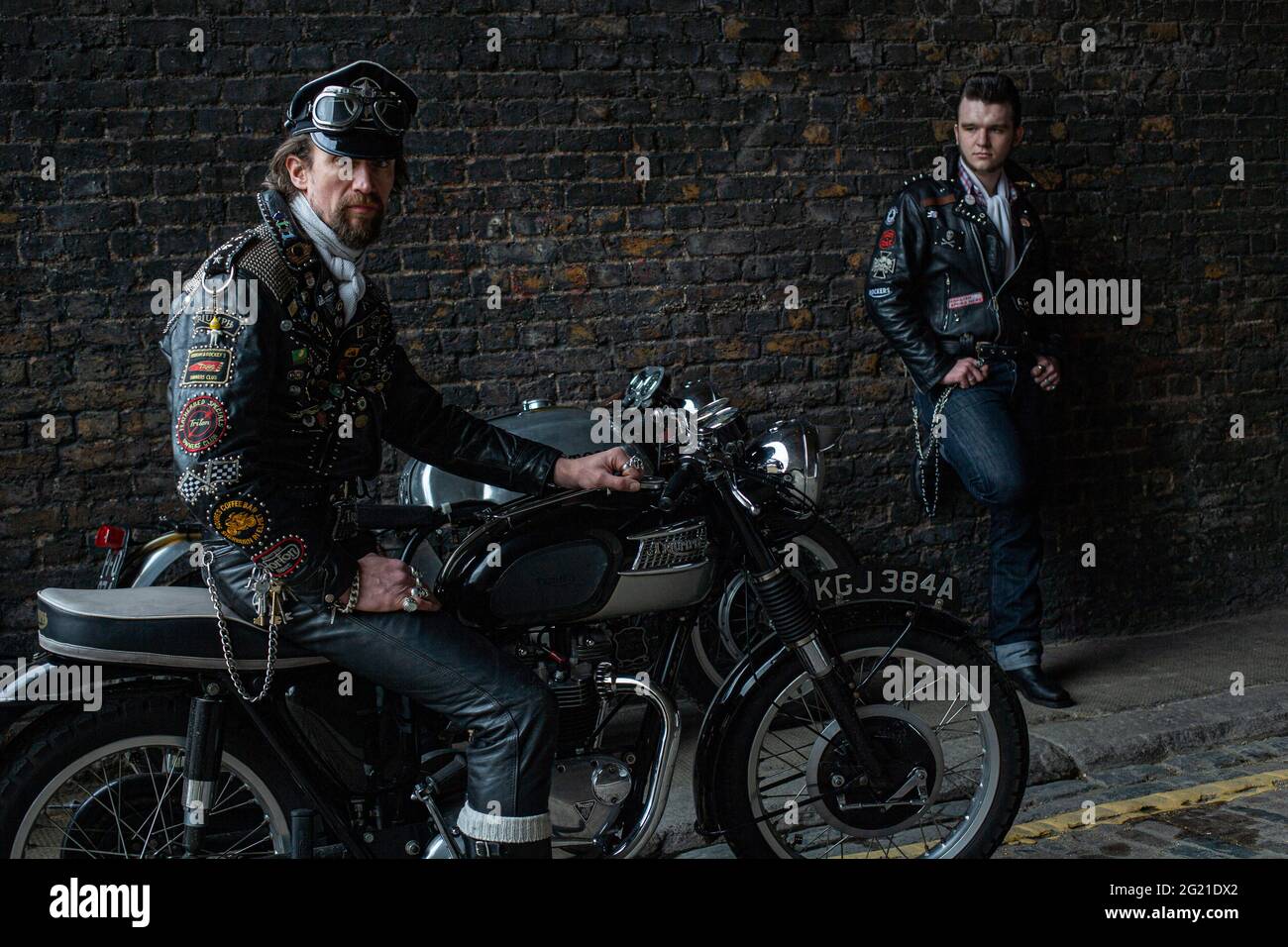 Zwei Rocker tragen schwarze Lederjacke mit Nieten, Patches und Abzeichen klassischen britischen Motorrad in London, Großbritannien bedeckt Stockfoto