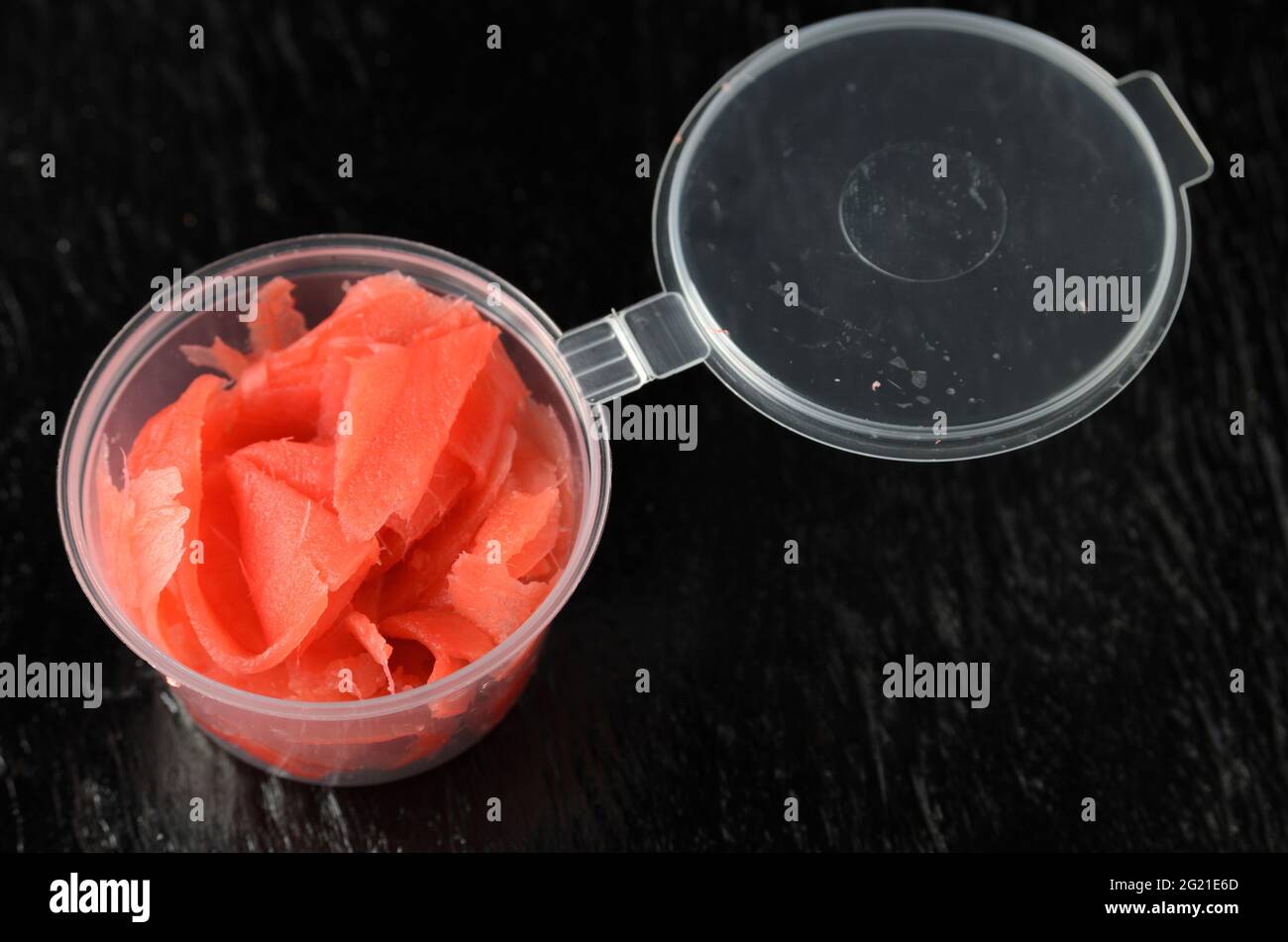 Ingwerwurzel in einem Plastikbecher in dünne Scheiben mit roter Farbe gehackt. Selektiver Fokus. Stockfoto