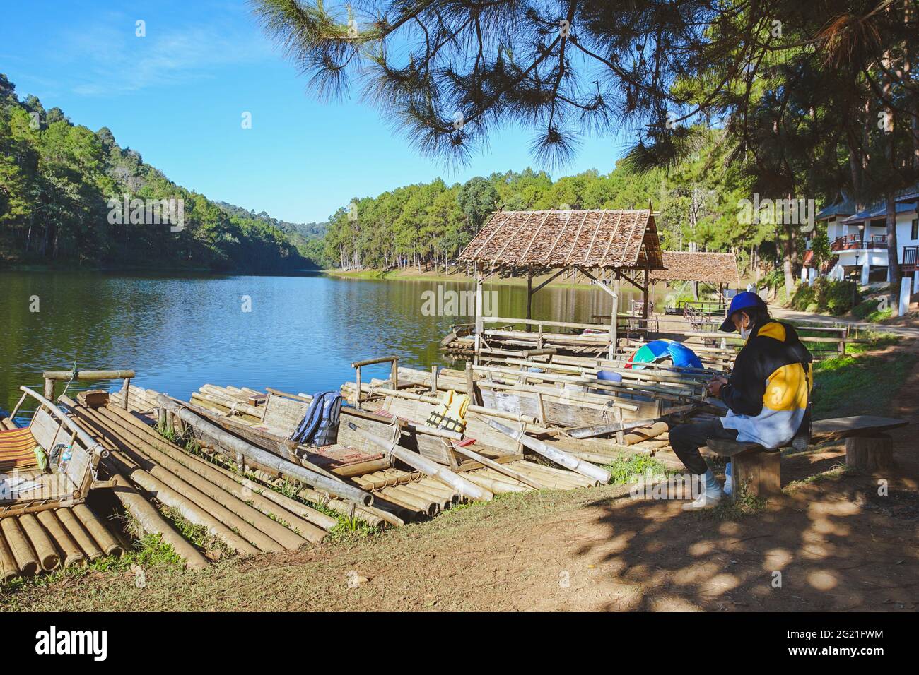 Mae Hong Son, Thailand - 15. Dezember 2020: Servicemitarbeiter des Pang Oung Floßes sitzt unter einer Kiefer am Pang Oung Reservoir. Stockfoto