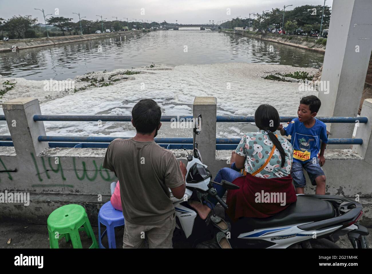 Jakarta, Indonesien. Juni 2021. Eine Familie blickt auf den verschmutzten BKT-Fluss Jakarta durch Hausmüll an der Marunda-Schleuse-Brücke. Der Schaum auf der Wasseroberfläche ist ein Hinweis darauf, dass der Kanal durch Haushaltswaschmittelabfälle verschmutzt ist. (Foto von Aslam Iqbal/SOPA Images/Sipa USA) Quelle: SIPA USA/Alamy Live News Stockfoto