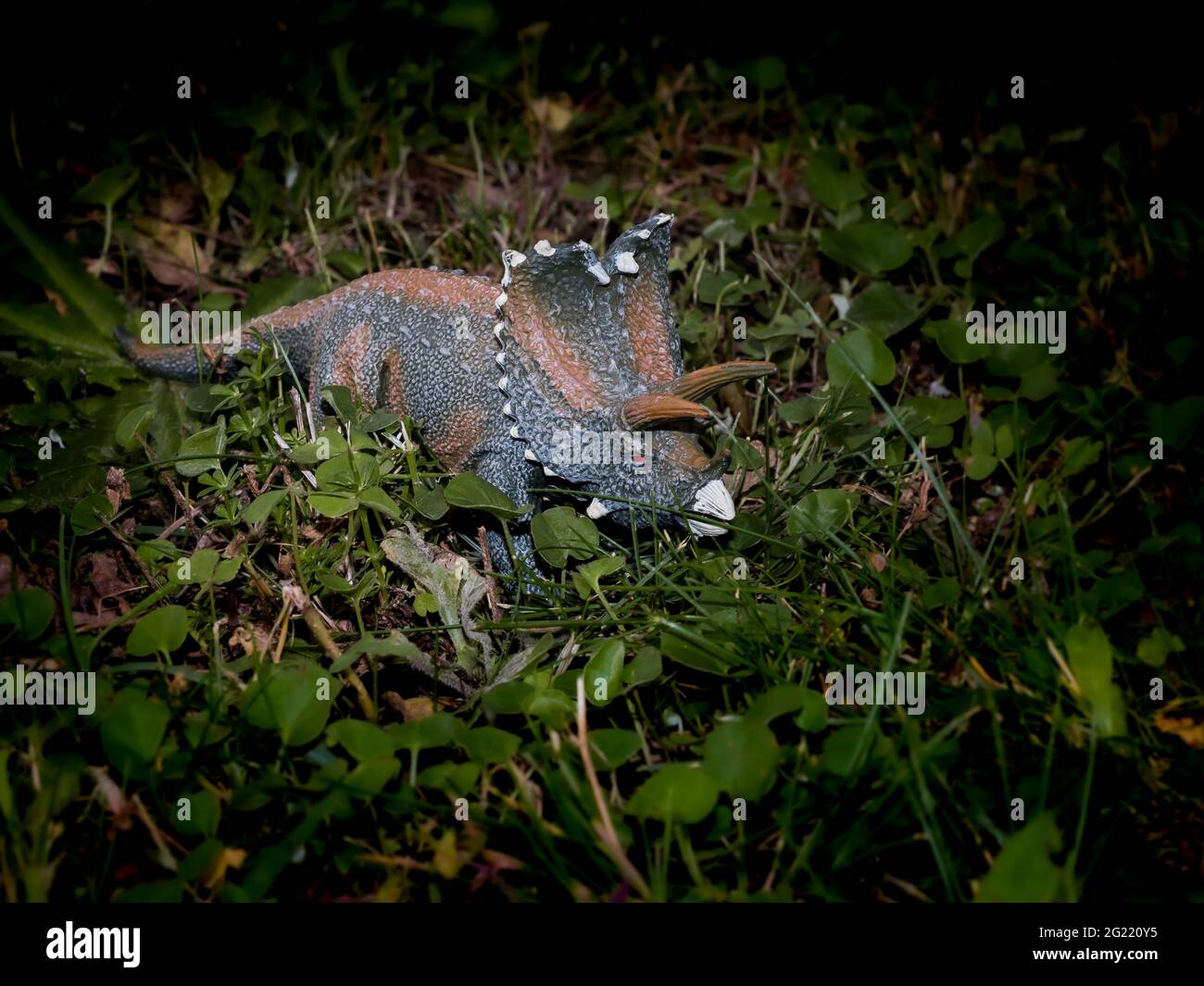 Stellen Sie ein Porträt des Spielzeug-Dinosauriers auf einem grünen natürlichen Hintergrund ein Stockfoto