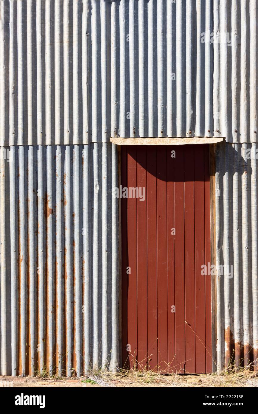 Eine rostrote Holztür in einer rostigen silbernen Wellblechwand mit Platz für Kopien. Stockfoto