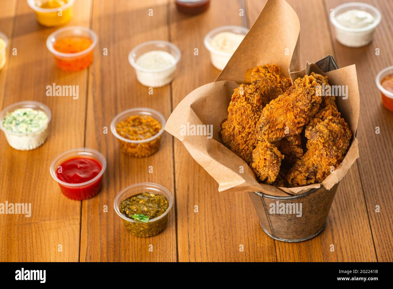 Frisch gebratene Hähnchenflügel und Tassen mit verschiedenen Saucen Stockfoto