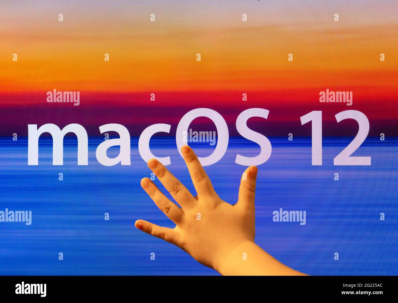 Los Angeles, USA - 7. JUNI 2021: Kinderhand auf dem Monitor mit einem Bildschirmschoner Makos 12. Neues Betriebssystem von Apple. Betriebssystem macOS Stockfoto