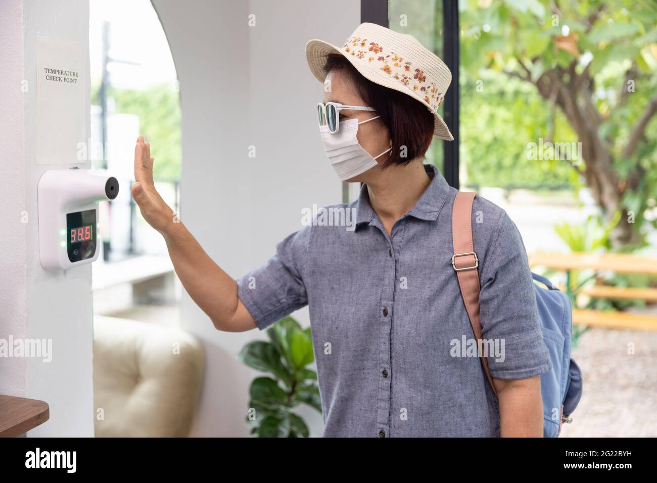 Weibliche Touristen benutzen das Infrarot-Thermometer, bevor sie das Restaurant betreten Stockfoto