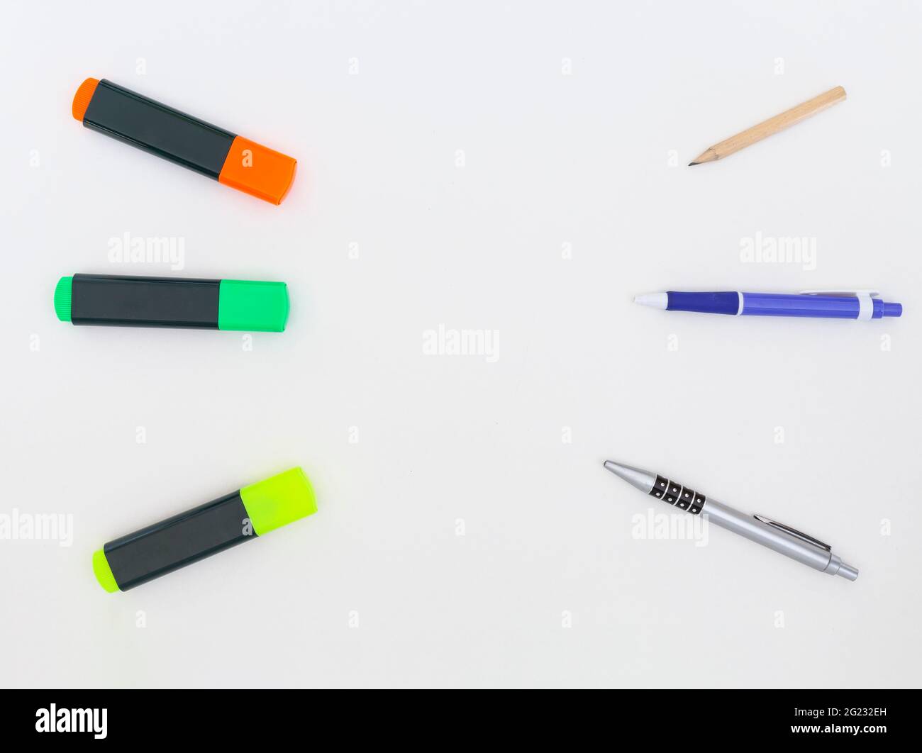 Gelbe, grüne und orange Textmarker, ein Bleistift und zwei Kugelschreiber auf weißem Hintergrund. Stockfoto