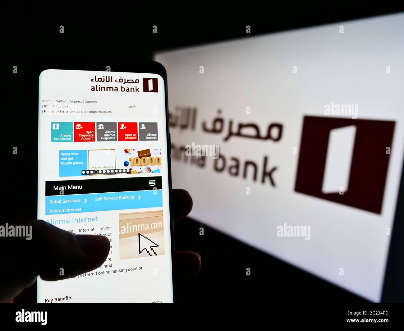 Person, die Smartphone mit Website des Saudi-arabischen Finanzunternehmens Alinma Bank auf dem Bildschirm vor dem Logo hält. Konzentrieren Sie sich auf die Mitte des Telefondisplays. Stockfoto