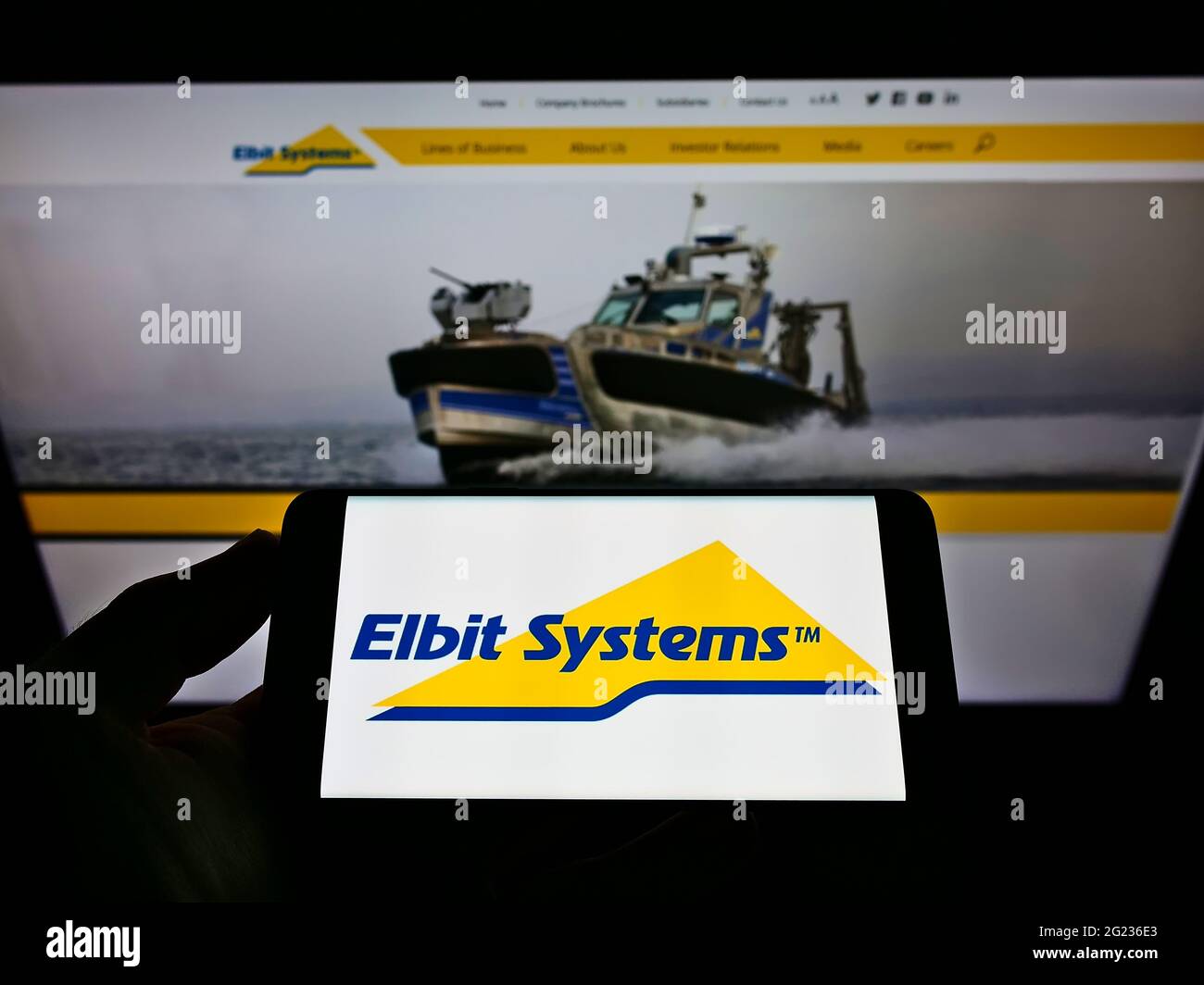 Person, die Mobiltelefon mit dem Logo der israelischen Verteidigungsfirma Elbit Systems Ltd. Auf dem Bildschirm vor der Business-Webseite hält. Konzentrieren Sie sich auf die Telefonanzeige. Stockfoto