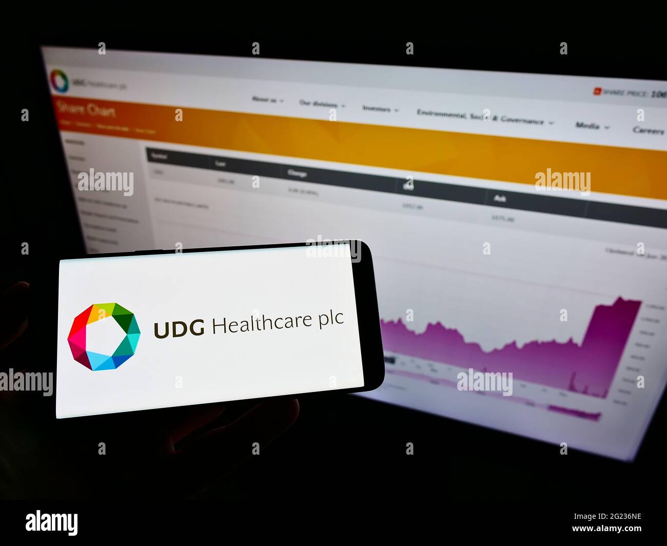 Person, die das Smartphone mit dem Logo des irischen Pharmaunternehmens UDG Healthcare plc auf dem Bildschirm vor der Website hält. Konzentrieren Sie sich auf die Telefonanzeige. Stockfoto