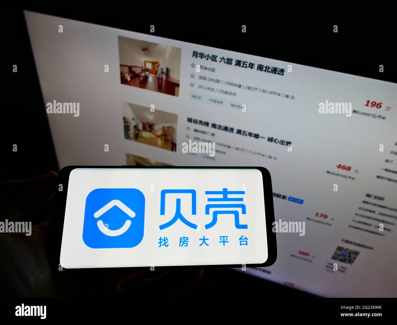 Person mit Mobiltelefon und Logo des chinesischen Immobilienunternehmens KE Holdings Inc. Auf dem Bildschirm vor der Webseite. Konzentrieren Sie sich auf die Telefonanzeige. Stockfoto