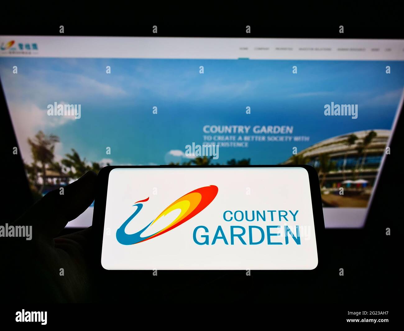 Person, die das Smartphone mit dem Logo der chinesischen Immobilienfirma Country Garden Services auf dem Bildschirm vor der Website hält. Konzentrieren Sie sich auf die Telefonanzeige. Stockfoto