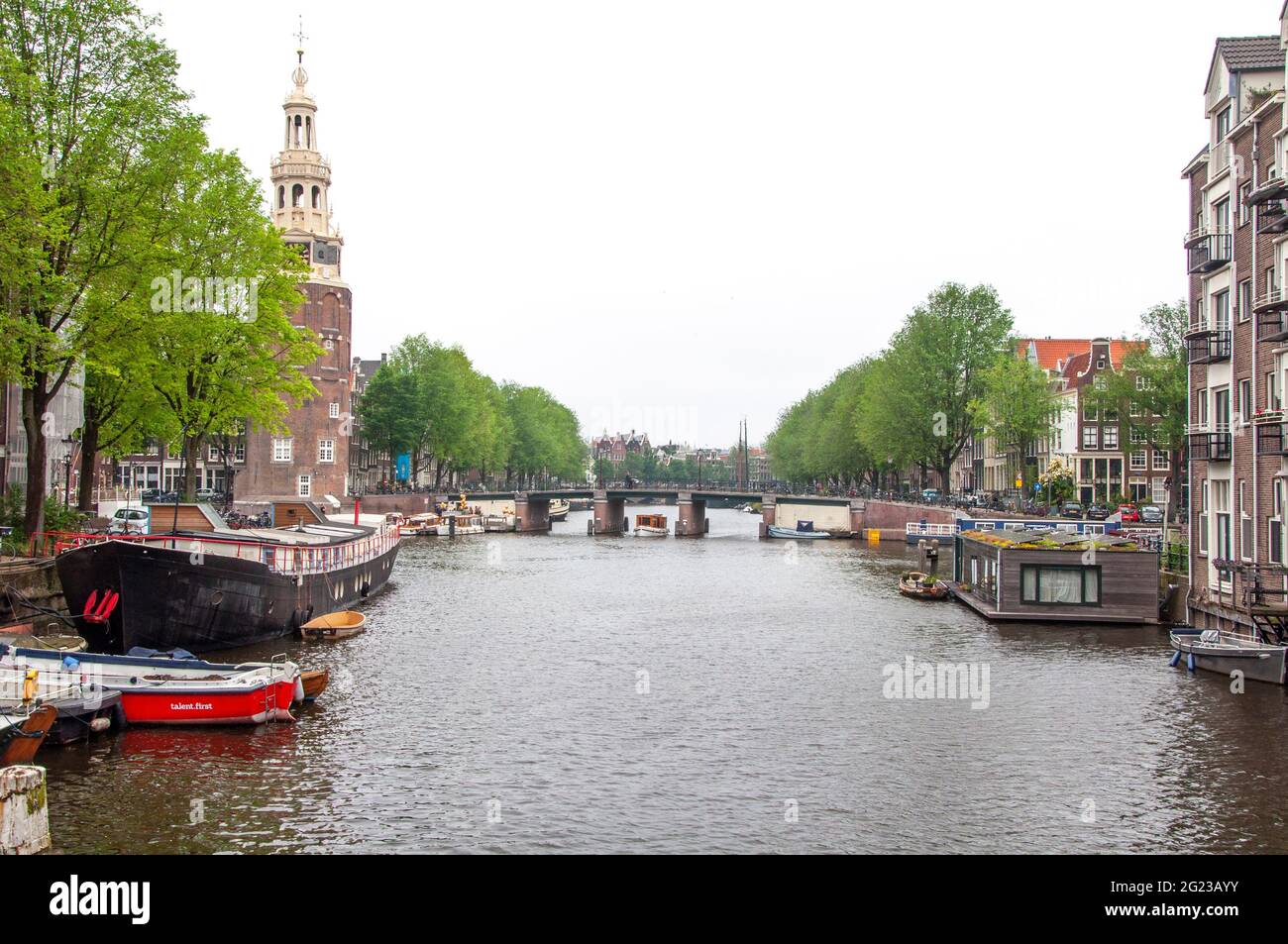 AMSTERDAM, NIEDERLANDE. 06. JUNI 2021. Schöne Aussicht auf Amsterdam mit typisch holländischen Häusern, Brücken und chanel. Kleine Boote auf dem Damm Stockfoto