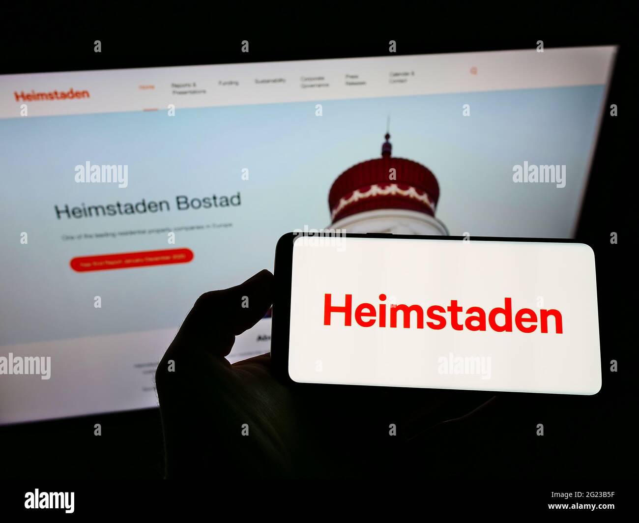 Person, die das Smartphone mit dem Logo des schwedischen Immobilienunternehmens Heimstaden ab auf dem Bildschirm vor der Website hält. Konzentrieren Sie sich auf die Telefonanzeige. Stockfoto
