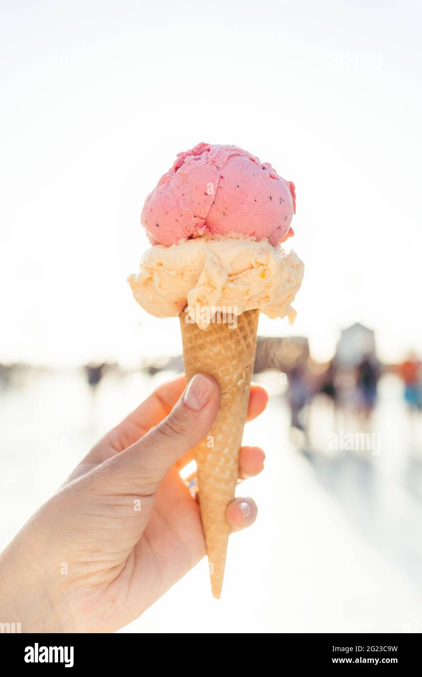 Die Hand der Frau hält Eis in Waffelkegel mit Hintergrundbeleuchtung. Stockfoto