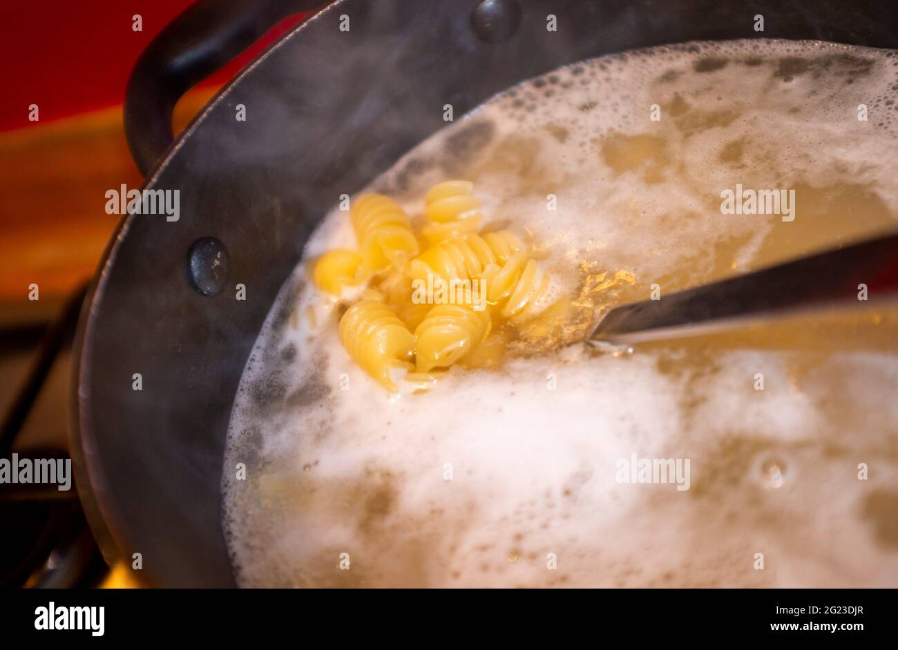 Kochen getrocknete Nudeln Formen in kochendem Wasser und Abtropfen Stockfoto