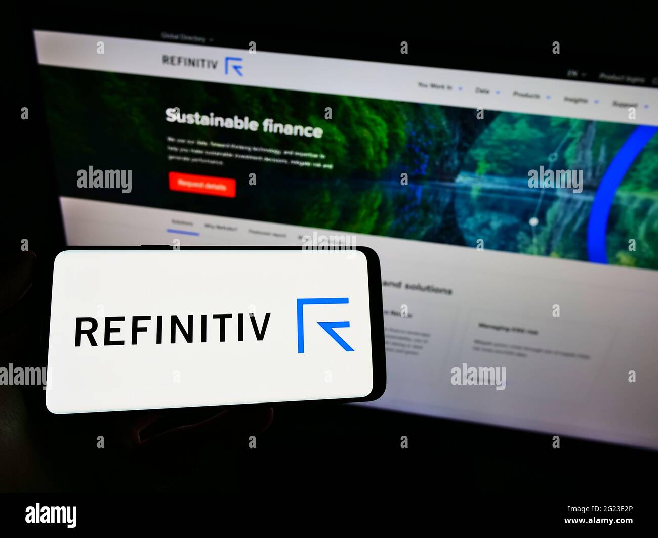 Person, die Mobiltelefon mit dem Logo der Finanzmarktdaten comapny Refinitiv Limited auf dem Bildschirm vor der Webseite hält. Konzentrieren Sie sich auf die Telefonanzeige. Stockfoto