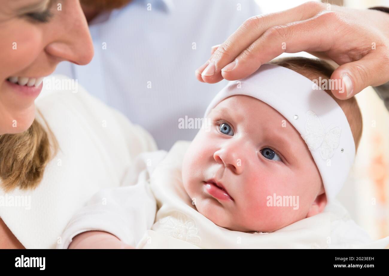 Mutter mit ihrem Baby bei der Taufe, mit der Priester seine Hand über die babys Kopf Stockfoto