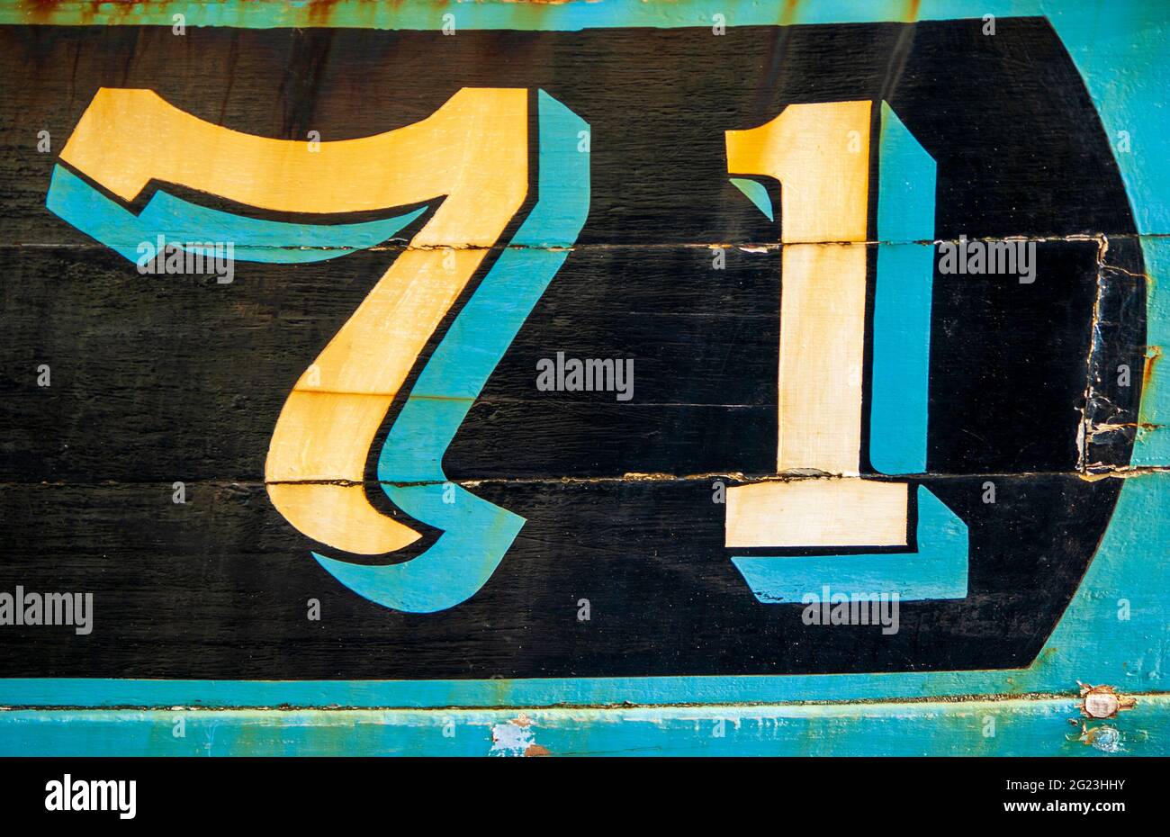 Die verwitterte Nummer 71 ist auf der Seite eines alten Fischerbootes gemalt, das am Girvan Harbour in South Ayrshire, Schottland, festgemacht ist. Stockfoto