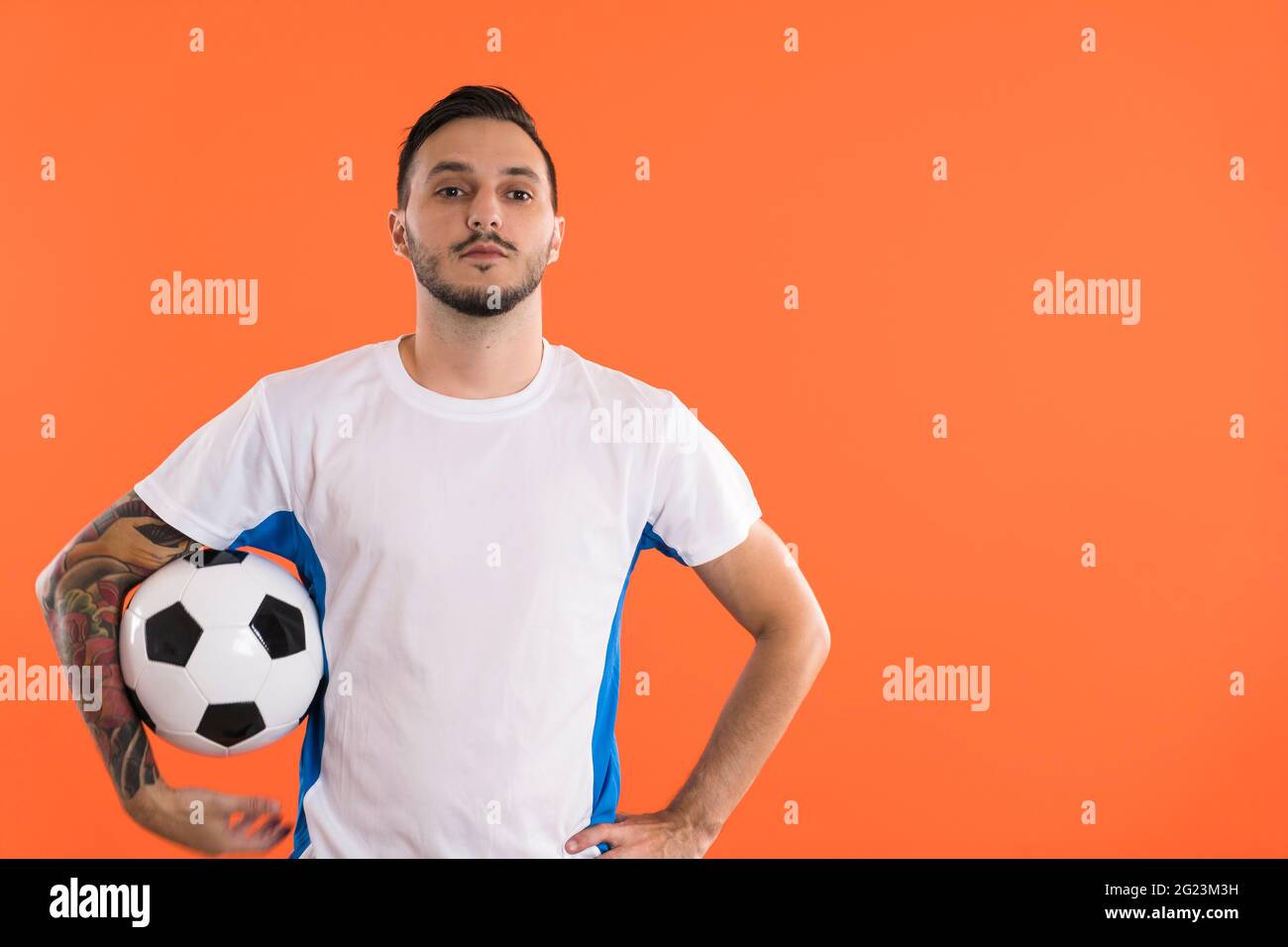 Ernst aussehende Fußballspieler isoliert auf orangefarbenem Hintergrund Stockfoto