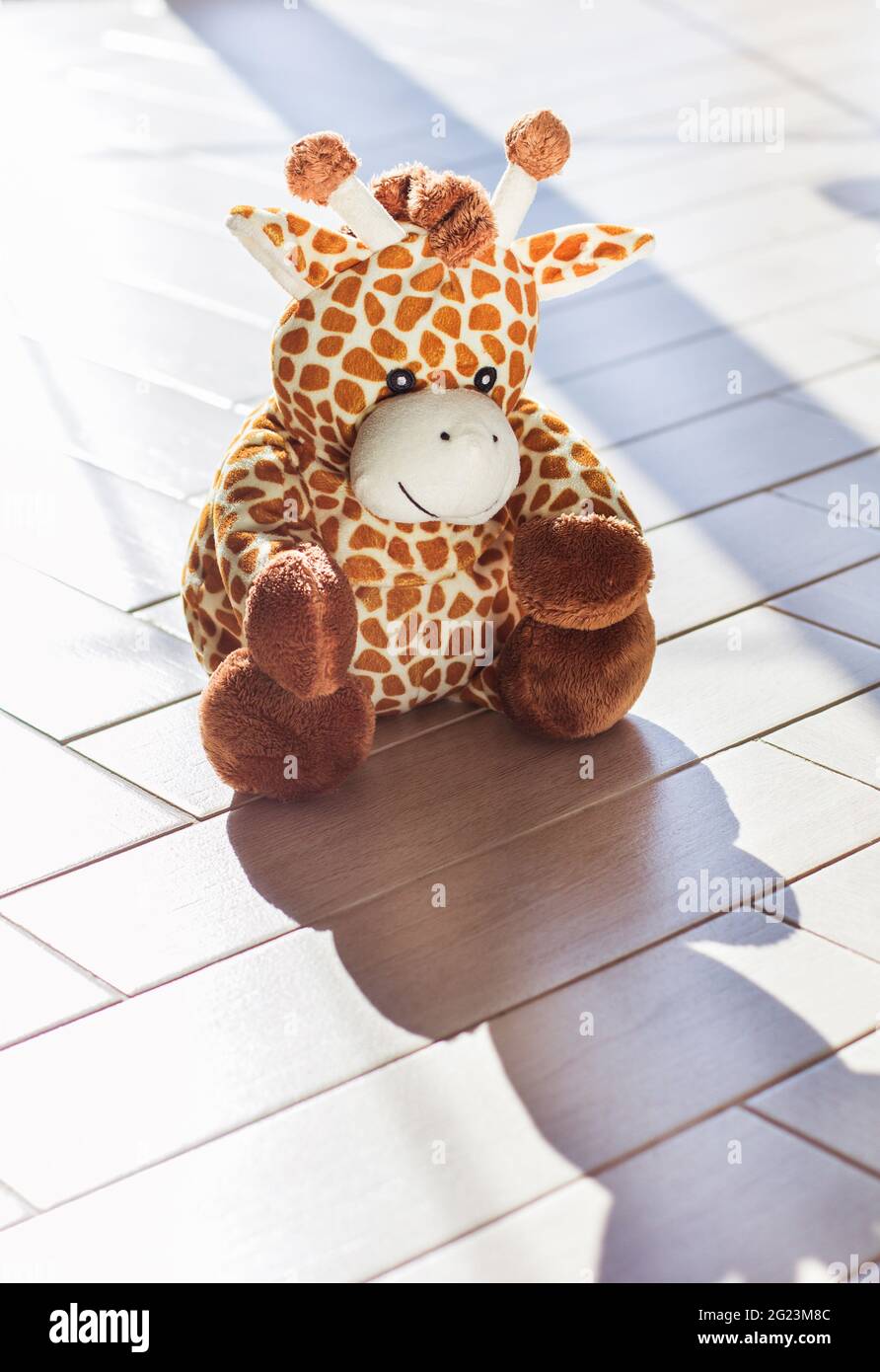 Die weiche Plüsch-Spielzeug-Giraffe für Kinder sitzt auf Holzhintergrund, hartem Licht und Schatten Stockfoto
