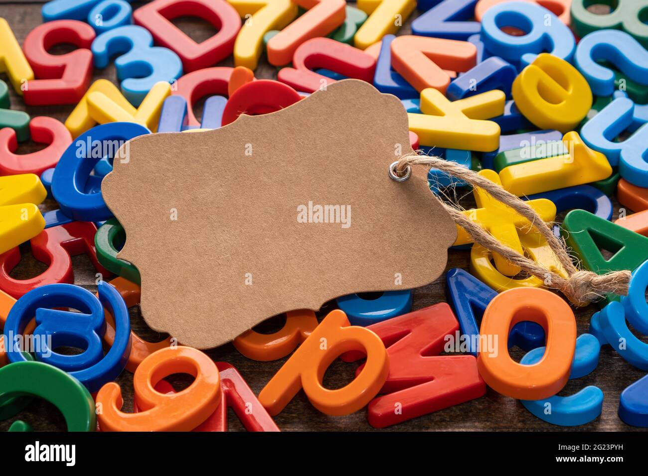 Blank Handwerk braunen Papier-Tag mit bunten Kunststoff-Alphabet auf Holzhintergrund Stockfoto
