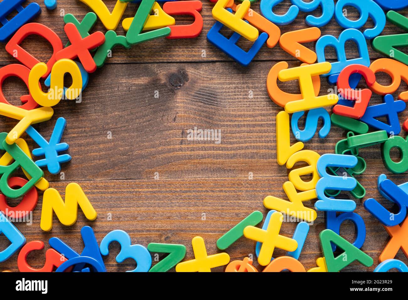 Draufsicht auf bunte Plastikbuchstaben und Zahlen auf Holzhintergrund Stockfoto