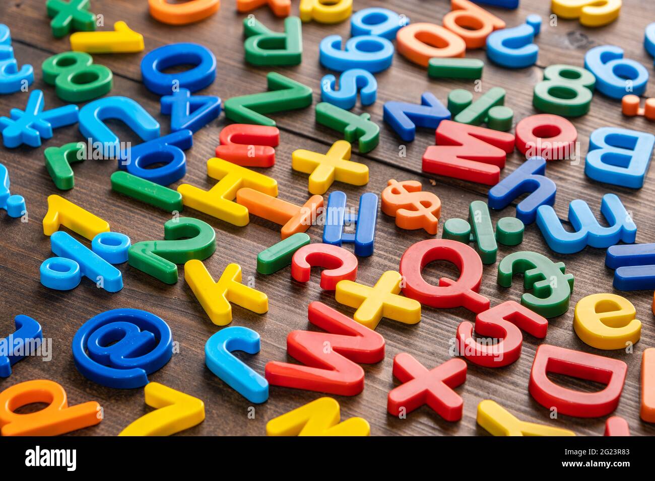 Draufsicht auf bunte Plastikbuchstaben und Zahlen auf Holzhintergrund Stockfoto