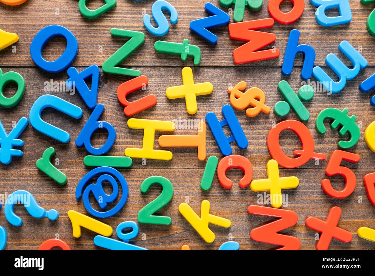 Draufsicht auf bunte Plastikbuchstaben und Zahlen auf Holzhintergrund Stockfoto