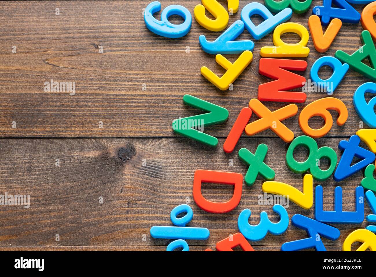 Draufsicht auf bunte Plastikbuchstaben und Zahlen auf Holzhintergrund Stockfoto