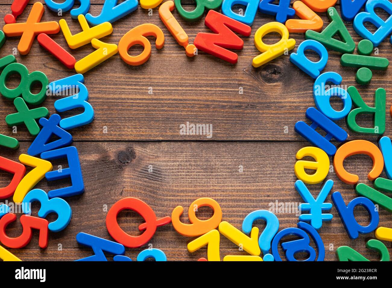 Draufsicht auf bunte Plastikbuchstaben und Zahlen auf Holzhintergrund Stockfoto