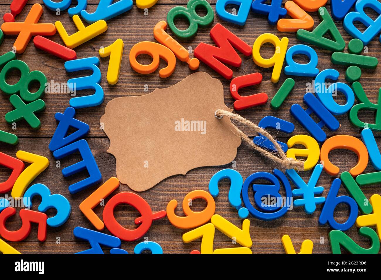 Blank Handwerk braunen Papier-Tag mit bunten Kunststoff-Alphabet auf Holzhintergrund Stockfoto