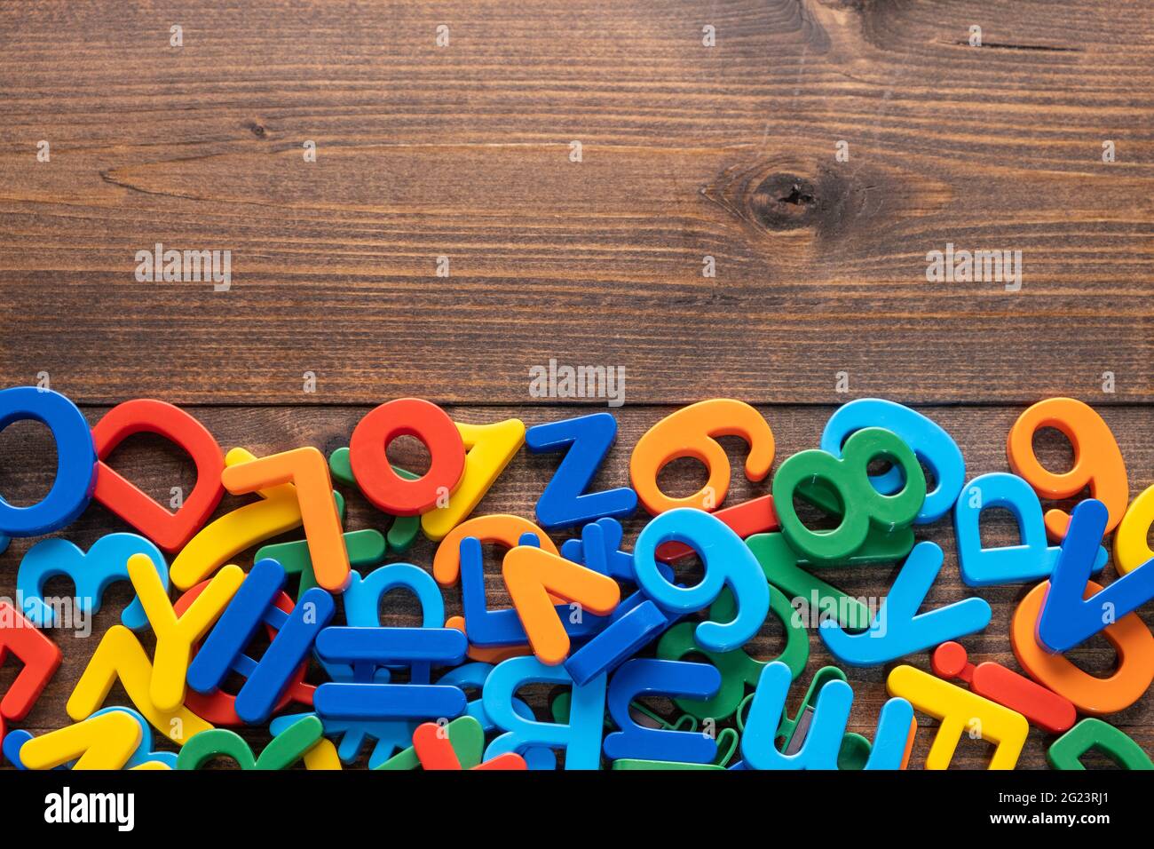 Draufsicht auf bunte Plastikbuchstaben und Zahlen auf Holzhintergrund Stockfoto