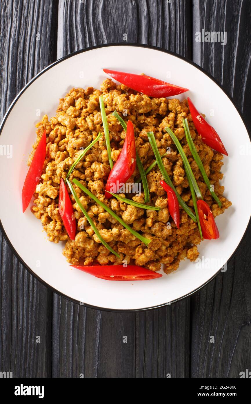 Khua kling ist eines der bekanntesten südthailändischen Gerichte, es ist ein trockenes, getrocknete, gehacktes Fleisch in der Nähe auf dem Teller auf dem Tisch. Vertikale Ansicht von oben Stockfoto